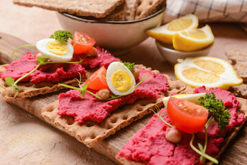 Crispbreads with tasty hummus on wooden board, closeup