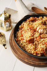 Frying pan with tasty Asian pilaf on table