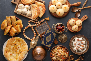 Traditional Eastern dishes with Quran, Arabic lamp and tasbih on dark background