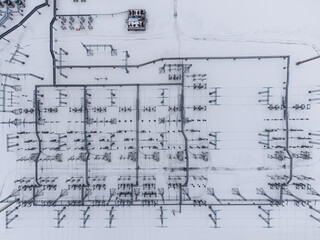 Aerial top-down view of a high voltage electrical substation in winter season.