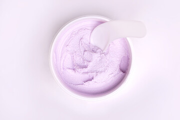 top view of a white jar of pink with a gentle face cream on a white background.