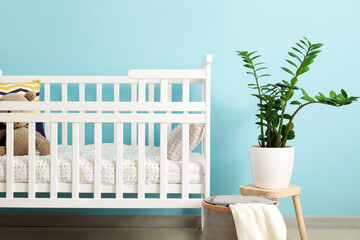 Baby crib with toy near color wall in children's room
