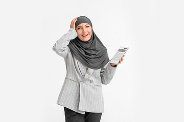 Stressed Muslim secretary with calculator on light background