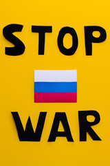 Top view of russian flag and stop war lettering on yellow background.