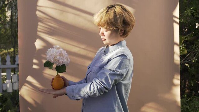 woman dancing outdoors by wall with shadow holding orange with flower