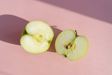 cut green apple on a delicate lilac-pink background. place for copywriting. two halves of a green apple.