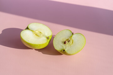 cut green apple on a delicate lilac-pink background. place for copywriting. two halves of a green apple.