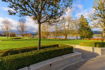 Looking across Rocky Point Park, Port Moody, BC, on a blustery Spring day, towards open air pavilion, with water and mountain backdrop.