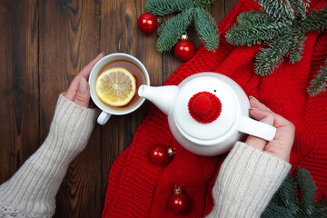 Women's hands pour tea from a teapot into a cup