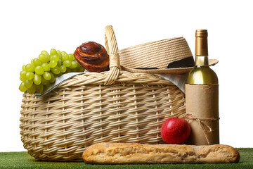 Wicker basket with tasty food and wine for picnic with hat on white background