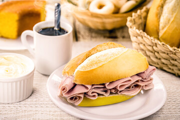 typical brazilian snack, pão de sal with slices of mozzarella cheese and ham, french bread for...