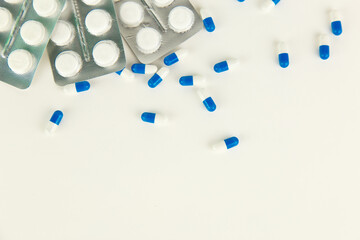 falling blue pills on pile of capsules on white background