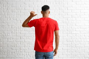 Handsome young man in stylish t-shirt on white brick background, back view