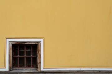 small wooden window on a yellow wall
