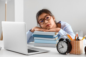 Tired little Asian girl in eyeglasses studying Literature with online tutor at home - obrazy, fototapety, plakaty