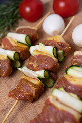 Raw lamb skewers with zucchini slices on wood