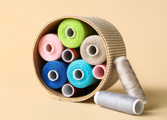 Box with different sewing thread spools on light background