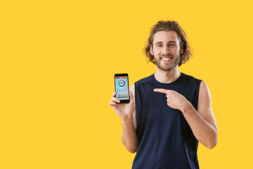Sporty man holding phone with installed app for calories counting on color background