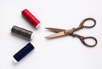 Thread spools and scissors on white background