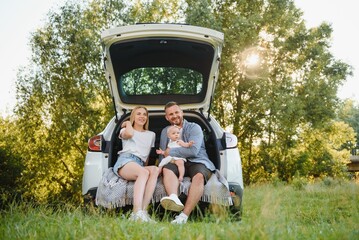 Happy family near car trunk on sunny day. Road trip