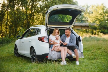Family with kid sitting in car trunk