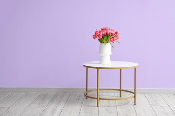 Vase with tulips on table near color wall in room