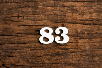 Number 83 in wood, isolated on rustic background