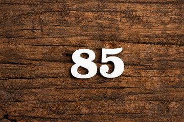 Number 85 in wood, isolated on rustic background