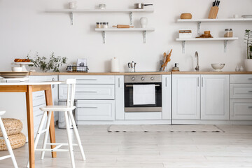Interior of stylish kitchen with shelves and dining table