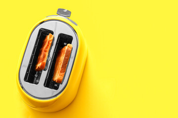 Modern toaster with bread slices on yellow background