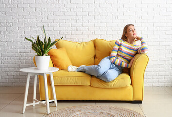 Obraz premium Pretty young woman relaxing on sofa at home