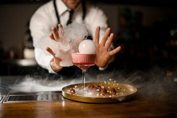 Pink foamy cocktail in champagne glass decorated with smoke air bubble.