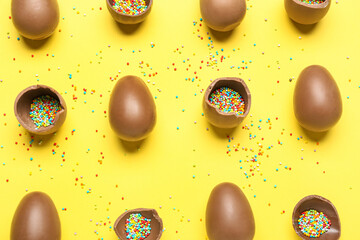 Delicious chocolate eggs with sprinkle fillings on yellow background