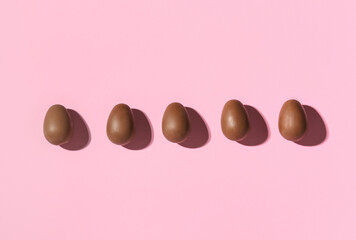 Delicious chocolate eggs on pink background