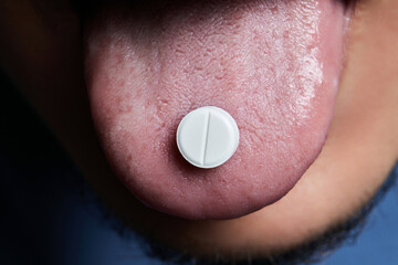 Man taking pill, mouth open with tongue sticking out.