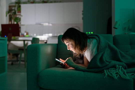Bored woman surfing internet in dark room at night. Addicted millennial female suffer from gadget and smartphone addiction, sleep disorder problem spend time in social media online before go to sleep.
