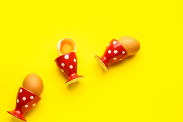 Fresh chicken eggs in holders on yellow background