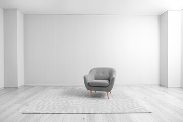 Grey armchair and carpet near light wall in big room