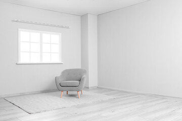 Grey armchair and carpet near light wall in big room