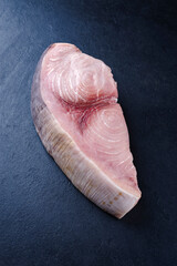 Raw swordfish steak offered as close-up on a black board with copy space