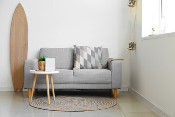 Interior of light living room with wooden surfboard and sofa