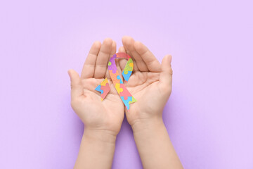 Child with awareness ribbon on lilac background. Concept of autistic disorder