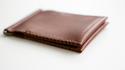 Empty men's money clip handmade leather wallet with a two pockets for cards lies on a white table. Selective focus, copy space, Close up.
