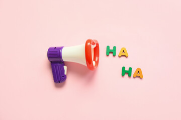 Composition with megaphone and text HA HA for April Fools Day celebration on pink background