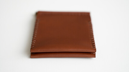 Orange men's money clip handmade leather wallet. Empty money clip wallet with a two pockets for cards lies on a white table. Selective focus, copy space.
