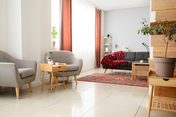 Interior of cozy living room with vintage carpet, armchairs and tables