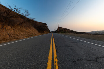 road with yellow line between hills