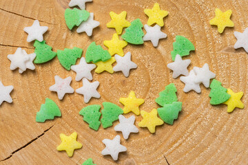 Star and Christmas tree-shaped traditional cake sprinkles on cracked pine tree wood slice