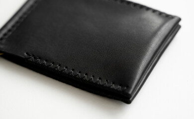 Black men's money clip handmade leather wallet. Empty money clip wallet with a two pockets for cards lies on a white table. Selective focus, copy space.