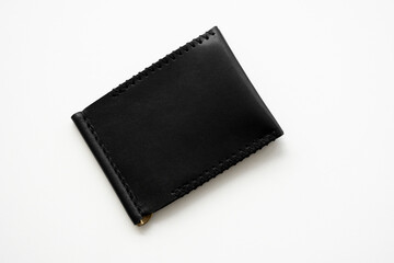Black men's money clip handmade leather wallet. Empty money clip wallet with a two pockets for cards lies on a white table. Selective focus, copy space.